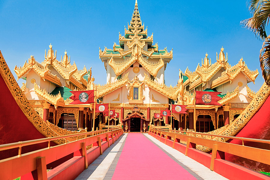 Biały pałac bogato zdobiony złotymi ornamentami z zielonym dachem. Do wejścia prowadzi most z czerwonym dywanem. Wzdłuż mostu rozwieszone czerwone flagi.