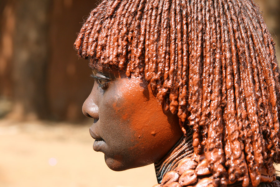 Twarz mieszkańca Etiopii z profilu. Patrzy w lewo. Włosy i policzek ma polamowane brązową farbą.