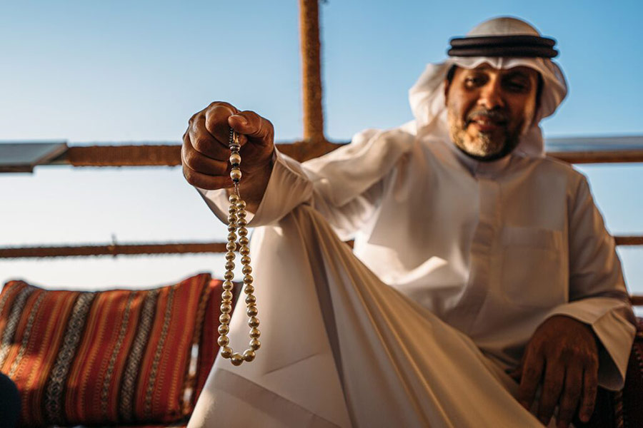 Mężczyzna na farmie pereł trzymający naszyjnik z perłami - Ecco Travel, Ras Al Khaimah